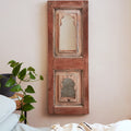Coffee brown coloured teak mirror hanging from a cream wall